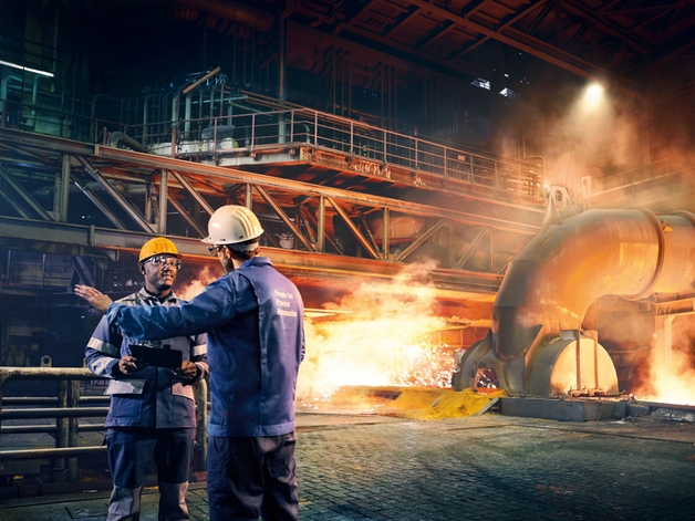 Två ingenjörer diskuterar på en metallfabrik.